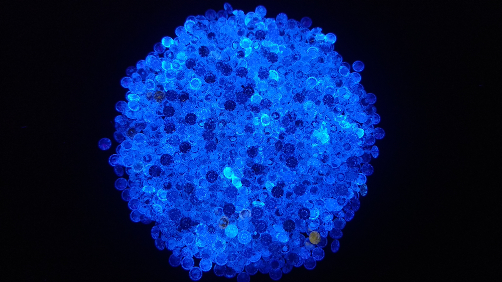 Small natural polished diamonds under an ultra violet light in a dark room showing none faint medium strong blue fluorescence