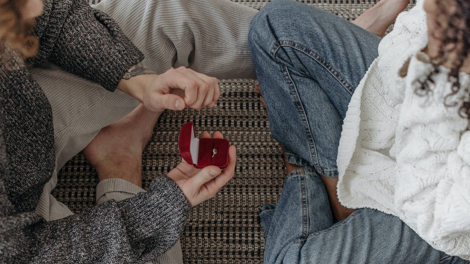 Guy proposing intimately at home with red box and engagement ring