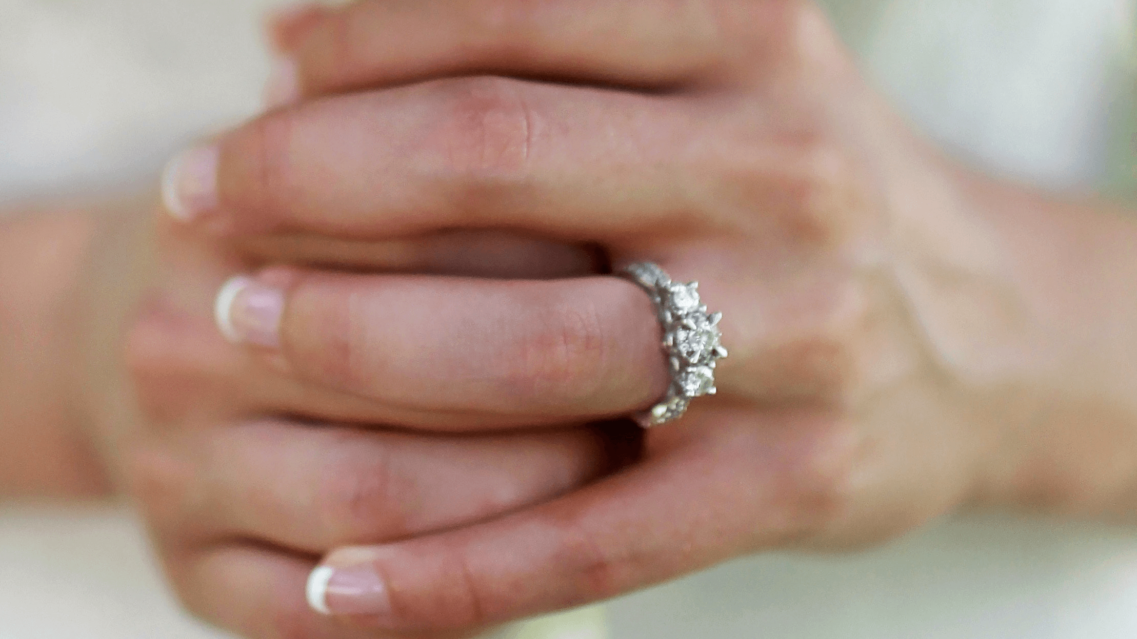 Newly engaged female with Three Stone diamond ring holding flowers- Three Stone Settings